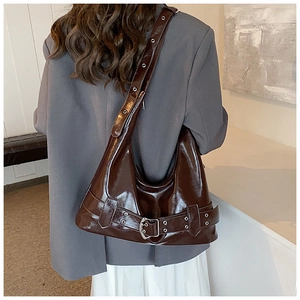 Detail of dark brown glossy leather hobo bag with eyelet strap and buckle decoration
