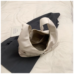 Detail shot of the cream-colored hobo bag interior with zipper pocket and metal buckles