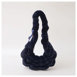 Detail van marineblauwe pluche wolktas met zacht geplooid imitatiebont en een strikhanger