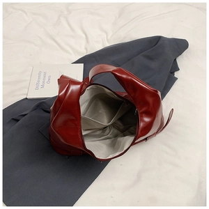 Detailed interior of glossy dark red shoulder bag with gray lining and zipper pocket