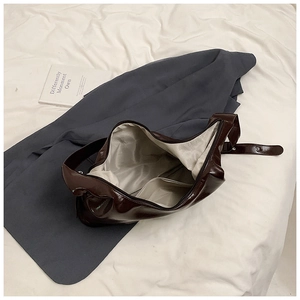 Top view of large brown glossy leather hobo bag with fabric lining and metal zipper