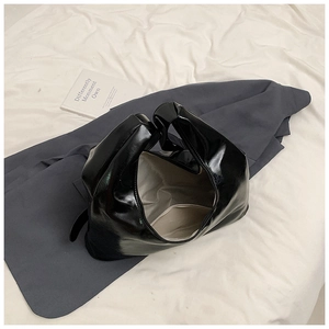 Detailed top view of black patent leather shoulder bag with zipper and spacious interior