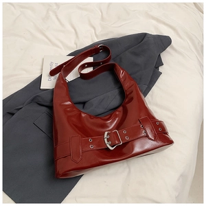 Detail of burgundy glossy leather hobo bag with silver buckle on grey blazer