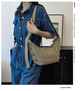 Detail of khaki crescent shoulder bag with quilted texture and metal eyelet accents