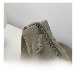Detail view of olive green nylon bag featuring a smooth black metal zipper with long pull tab