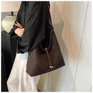 Detail of deep brown PU leather tote bag with drawstring closure and knotted shoulder strap