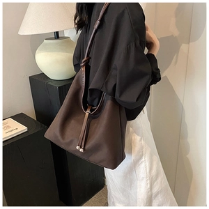 Detail of dark brown tote bag with matte texture and drawstring metal ball charm