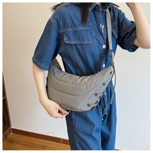 Detailed view of grey quilted crossbody bag with side drawstring and adjustable strap