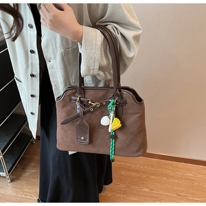 Detail der dunkelbraunen Wildleder-Schultertasche mit Baseball-Schläger- und Handschuh-Anhang