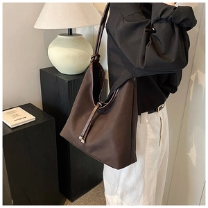 Detail of coffee brown tote bag with suede texture and leather knotted strap detail