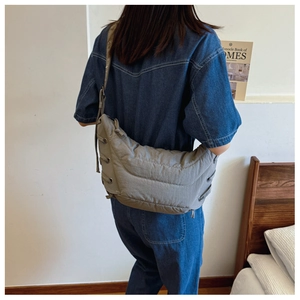 Detail view of a grey quilted crescent shoulder bag with drawstring side knots and strap