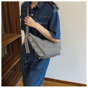 Detail of gray quilted nylon crossbody bag with side eyelets and drawstring design