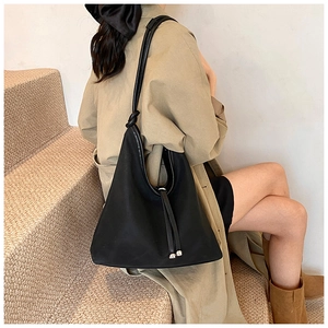 Detail of minimalist black oversized shoulder bag with knotted strap and drawstring