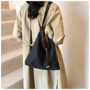 Detail of a black crossbody tote bag with knotted strap and metal bead drawstring design