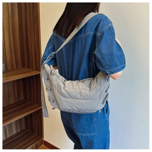 Detail view of light grey quilted crescent bag with side knot and metallic eyelets
