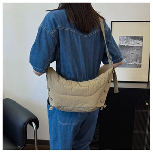 Quilted beige crescent bag with drawstring details styled on a casual blue denim jacket