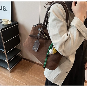 Detailansicht der braunen Wildledertasche mit Baseballhandschuh-Anhänger und Lederschnalle