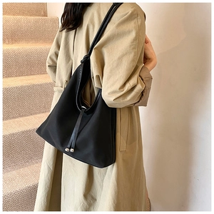 Detail of minimalist black PU tote bag with drawstring texture and silver beads on shoulder