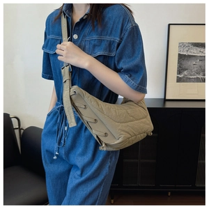 Detail view of the beige crescent shoulder bag with criss-cross side strap design