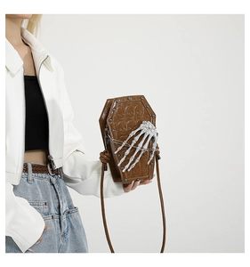 Brown coffin-shaped shoulder bag featuring skull relief details and white bone hand claw