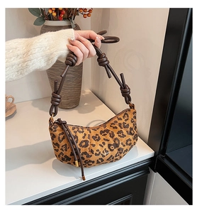 Détail du sac croissant à motif léopard avec texture en daim et poignée en cuir nouée