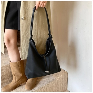 Detail of black nylon tote bag with leather drawstrings and silver metal ball accents