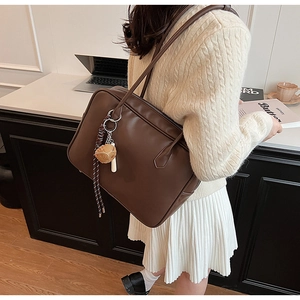 Détail du grand sac cabas en cuir PU marron foncé avec accessoire de sac et décor de bureau