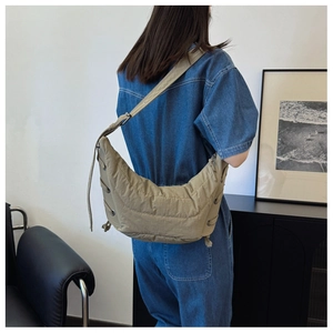 Detail of khaki crescent crossbody bag featuring quilted fabric and side drawstring knot