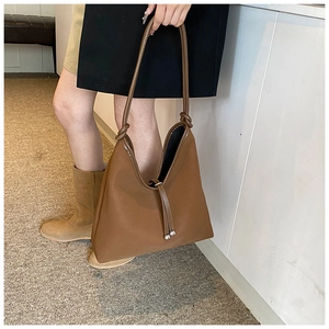 Detail view of brown matte PU leather shoulder bag with drawstring tassels and knot handle