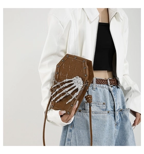 Detail view of a brown coffin-shaped PU shoulder bag with silver skeleton hand and rivets