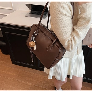 Détail du sac à bandoulière en cuir PU marron foncé avec petit accessoire de poupée