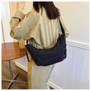 Rear view of a black quilted crescent crossbody bag with drawstring details and metal eyelets