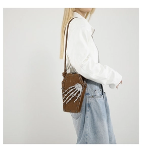 Macro view of coffin-shaped brown PU leather bag with silver skeleton hand and rivets