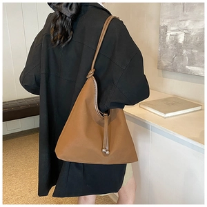 Detail of caramel brown hobo bag with knotted strap and delicate metal bead pendant