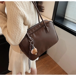 Détail d'un sac à bandoulière en similicuir marron avec pendentif gant de baseball