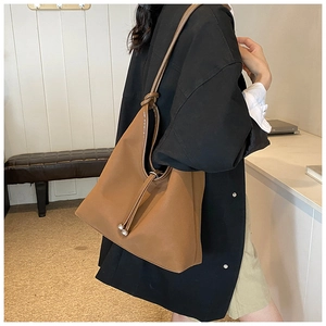 Detail of dark brown matte leather tote bag with knotted shoulder strap and drawstring closure