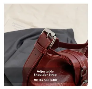 Detail shot of the adjustable shoulder strap with silver buckle on burgundy PU leather bag