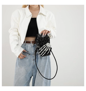 Detailed view of black coffin-shaped PU shoulder bag with white bone hand and skull texture