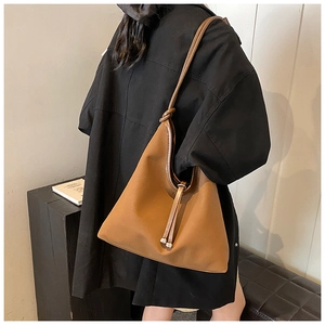 Close-up of caramel brown PU leather tote bag with knotted strap and tassel detail