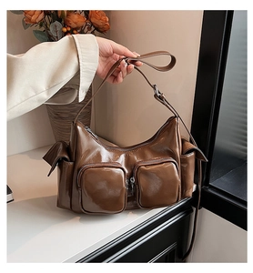 Detail of dark brown glossy PU leather shoulder bag with two square zipper pockets