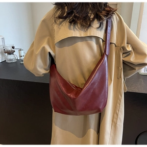 Deep red hobo crossbody bag in high-quality PU leather worn with a trench coat