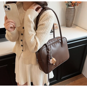 Détail d'un sac à épaule vintage en similicuir marron foncé avec un pendentif tendance
