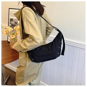 Close-up of black quilted moon bag featuring silver metallic grommets and wide strap