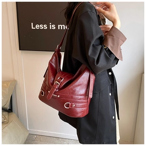 Detail of burgundy vintage PU leather shoulder bag with silver hardware on model