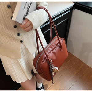 Détail d'un sac à épaule en cuir PU marron avec zip argenté et breloque décorative