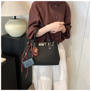 Detail of black PU leather tote bag with metal twist lock and unique decorative charms
