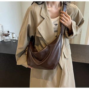 Detail of a large dark brown PU leather hobo bag worn by a model in a casual city setting