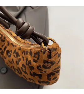 Gros plan du sac à bandoulière léopard en daim avec lanière en cuir et détails dorés
