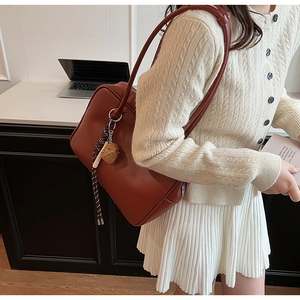 Détail du sac à épaule en cuir PU marron rouge avec pendentif dé décoratif sur mannequin