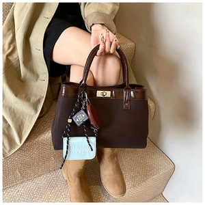Detailed close-up of dark brown PU handbag featuring a unique blue charm and metal twist lock